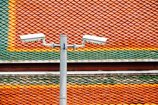 Surveillance cameras pointing down in front of orange tile background