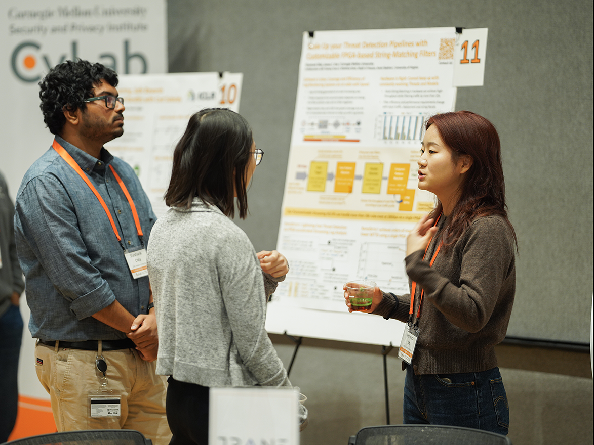 Photo of a student presenting her research poster  to two onlookers at the CyLab Partners Conference